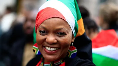 Woman wearing South Africa flag headscarf and earrings