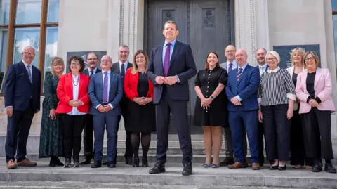 PA Media Rhun ap Iorwerth in the middle flanked by cabinet ministers