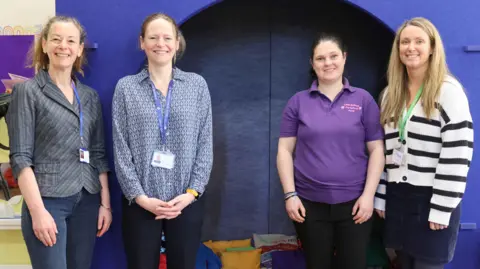 Emma Fraser, Head of the States’ Sensory Support Services, Leonie Burrows from Guernsey Deaf Children’s Society, Heidi de Mouilpied, Manager at Little Buttons Preschool and Zara Betts, Specialist Early Years Speech and Language Therapist all stood at the entrance to the pod. They are all smiling and looking directly at the camera. 