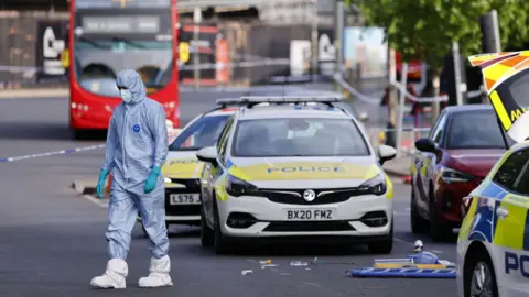 Forensic police officers inspect the scene where two Jewish men are seriously injured after being stabbed in Golders Green