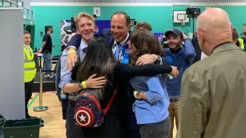 Miles Blumsom/BBC Greg Smith hugs three people at election count