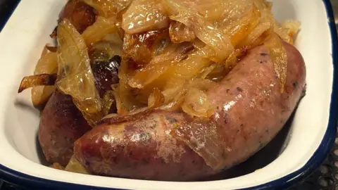 Kevin Shoesmith/BBC A dish contains thick butcher's sausages and fried onions.
