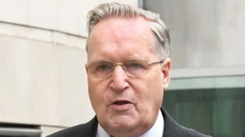 Alan Lewis/Photopress Paul Dunleavy, with grey hair and glasses. in a suit and jacket