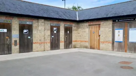 Frome Town Council A courtyard lined by a row of toilet doors. 