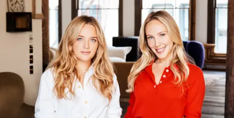 Leslie Kirchhoff Charlotte Cruze with her co-founder of Alice Mushrooms Lindsay Goodstein. Charlotte has a white blouse and Lindsay a red top and both have long blond hair.