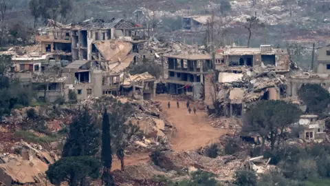 Atef Safadi / EPA IDF soldiers walk through a village in southern Lebanon with burnt-out buildings and rubble against the backdrop of the southern Lebanese countryside, taken on Sunday from the border.