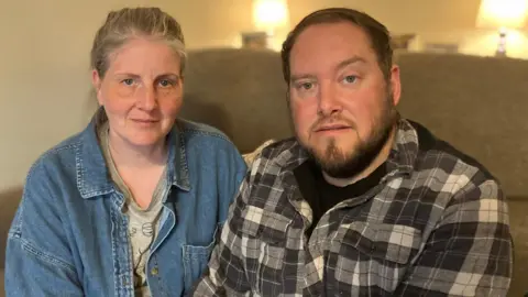Sarah and Gary Andrews, sat at home. looking at the camera