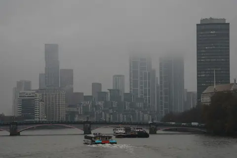 Getty Images A catamaran makes it way down the Thames towards high-rise buildings partly obscured by clouds in London 