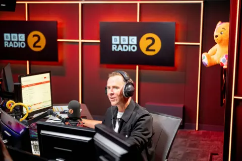 Scott Mills in the Radio 2 studio with headphones on