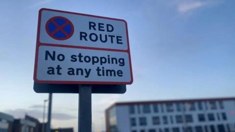 A red route sign notifying drivers that they must not stop at any time