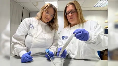 Madeline Berrow and Dr Felicity De Cogan stood watching a sample of their antimicrobial resin dry.