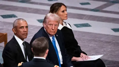 Getty Images Melania Trump sits next to her husband Donald Trump and former President Barack Obama