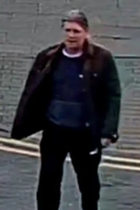 Lincolnshire Police A zoomed in photo of the man in the CCTV as he crosses the road. He is wearing dark clothing and has grey or brown hair.