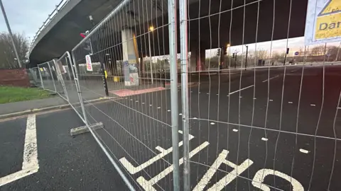 LDRS Metal fences blocking off the road underneath the flyover and a pedestrian crossing.