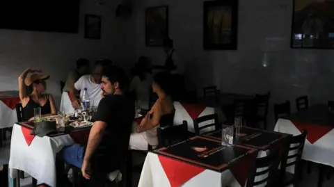 Orang -orang Reuters duduk di dalam sebuah restoran setelah pemadaman listrik yang besar melanda petak besar negara itu, di Santiago, Chili 25 Februari 2025.