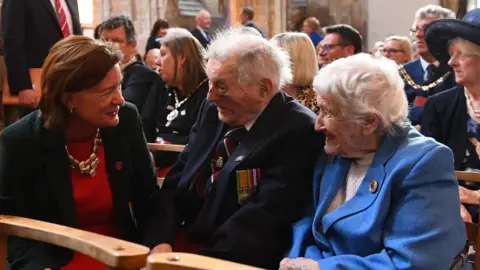 Welsh Government Eluned Morgan speaking to a veteran, who has white hair and is wearing a dark blazer