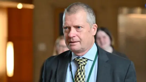 Getty Images Graham Simpson, who has short grey hair, in a close-up shot. He is wearing a dark suit, light blue shirt and yellow patterned tie. 