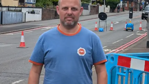 Resident David Broome stood by roadworks signs on City Road