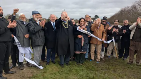 Bedford Borough Council Attendees standing on the field cheering for camera 