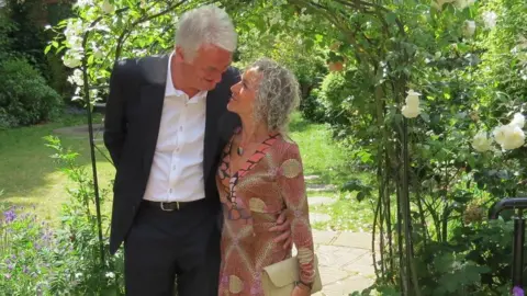 SUPPLIED A couple standing in front of a garden arch