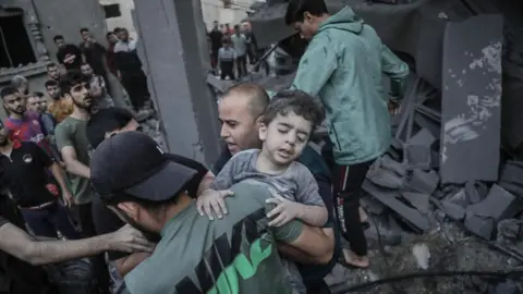 EPA A child is recovered from the rubble of a building hit in an Israeli airstrike, in Khan Younis refugee camp, in Gaza (October 2023)