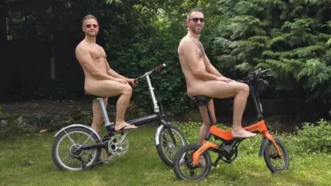 Shayne and Stephen post on their bikes naked.