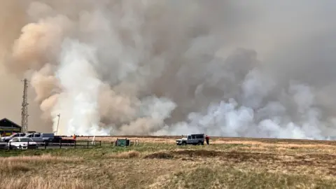 A fire in Goyt Valley issuing plumes of white smoke into the sky