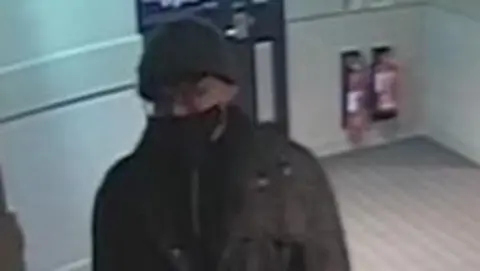 CPS Grainy still from CCTV of Kwan wearing a face mask and hat as he leaves a hotel.