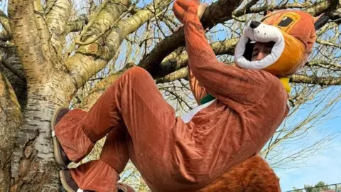 Acorn Centre, Jersey Employment Trust Dressed in a red squirrel costume a staff member climbs a tree on the Highlands College Campus.