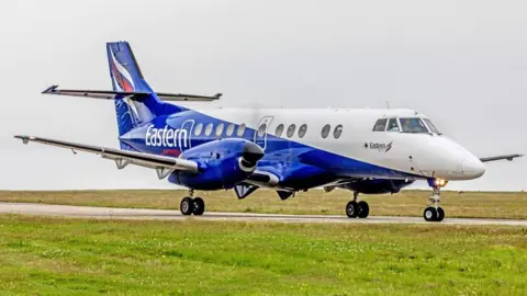 Airteamimages.com A blue and white plane taxiing on a runway.