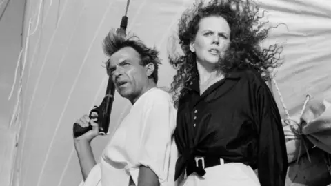 Michael Ochs Archives/Getty Images Actor Sam Neill and Actress Nicole Kidman on the set of the Warner Bros movie "Dead Calm" circa 1989. He is holding a gun