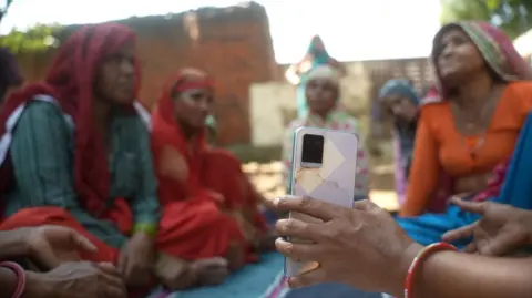 Saraskanth TK A woman gives her phone to a group of friends in the Indian state of Haryana