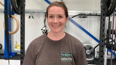 Alex Pope/BBC Laura Barnes standing in front of gym equipment in a Stagsden gym