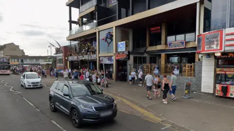 A row of businesses is pictured with large crowds of people