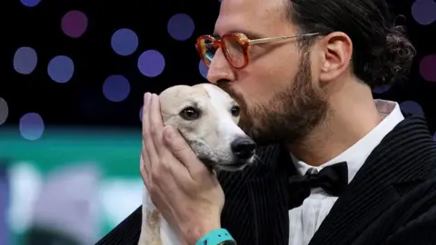 Dog handler Giovanni Liguori kisses his whippet and holds his hand to her ear