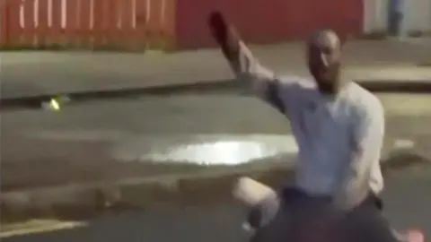 A image of a man with his hand up in the air. His face is blurred. 