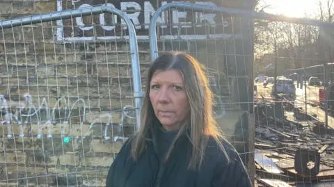 Steve Jones/BBC Kelly Hildreth stood next to fences surrounding her business. She wears a dark jacket and a neutral expression.
