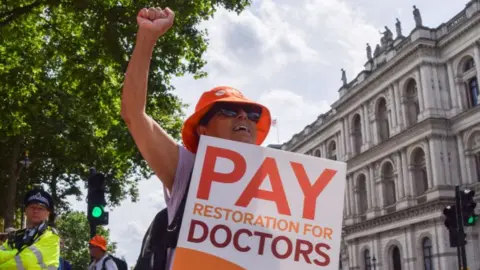 A junior doctor holds a placard in support of fair pay during a rally in London, England on 27 June 2024.