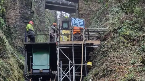 Lynton & Lynmouth Cliff Railway This is an image of the work taking place on the cliff. There is some scaffolding attached to the bank at the side of the track. There are a number of engineers on the scaffolding.