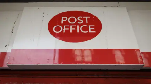 EPA-EFE/REX/Shutterstock An exterior view of the sign on a branch of the Post Office showing the company logo on a white background and a red stripe along the bottom of the sign