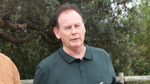 ABC News/Kelly Fuller Ricki Nash speaks to the camera, wearing a dark green shirt