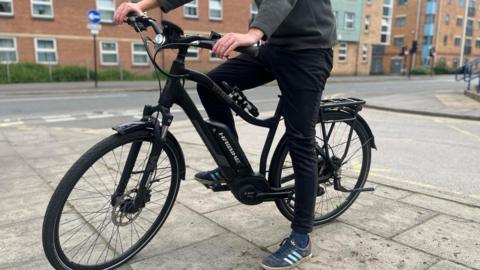 A man sitting on a black stationary e-bike