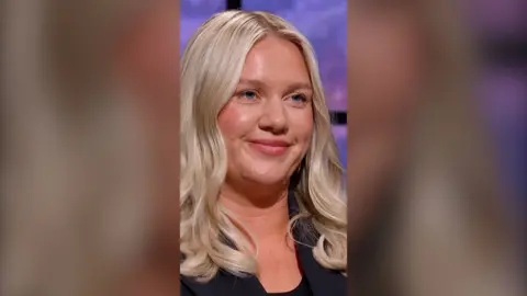 Businesswoman Jenna Meek appearing on Dragons' Den. She has long wavy blonde hair and is wearing a black jacket and top.