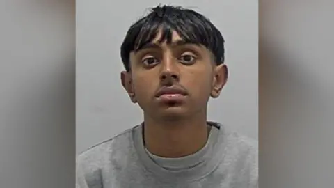 Bedfordshire Police Riaz Miah: The head and shoulders of a man with straight black hair, and black moustache. wearing a grey round-necked top.