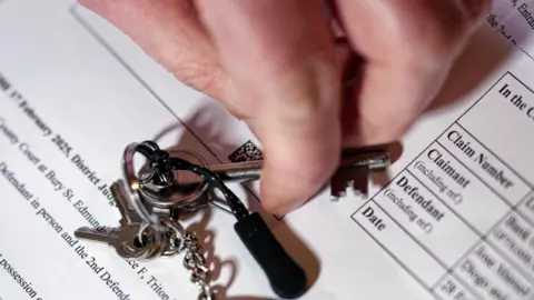 Laurence Cawley/BBC A close-up image of Jose's hand, lightly touching his keys on top of the court decision document stating his home will be repossessed.
