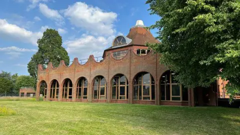 The outside of Pippbrook House, an building with big glass windows and a wavey brick design.