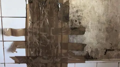 GMTU Mouldy bathroom wall taped over