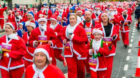 Runners taking part in the Liverpool Santa Dash in 2022. They are all wearing santa suits.