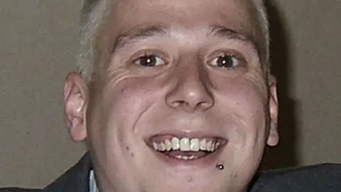 PA Media A close-up of Phil Beer who has short blonde hair and his chin raised and is smiling broadly. He has a stud under his lip on the left. His grey jacket can just be seen.