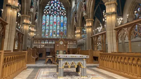 Cathedral altar in front of a large stained glass window.